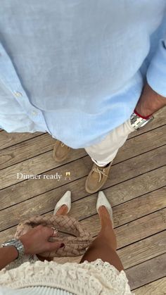 two people standing next to each other on a wooden floor with their feet in the sand