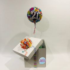 an open box with balloons and streamers in it