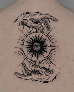 a man's back with two hands holding an all seeing eye tattoo on it