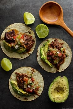 three tortillas with meat, avocado and salsa on a black surface