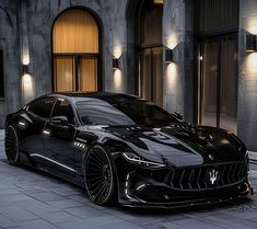 a black masera is parked in front of a building with lights on the side