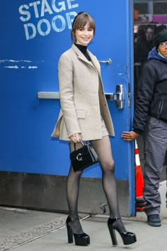 a woman in tights and heels is standing by a blue door