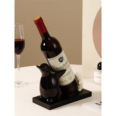 a bottle of wine sitting on top of a black elephant figurine next to a glass of wine