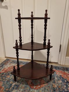 a wooden corner shelf sitting on top of a rug