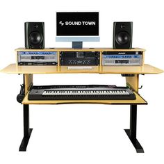 an electronic keyboard sitting on top of a wooden desk next to a monitor and speakers