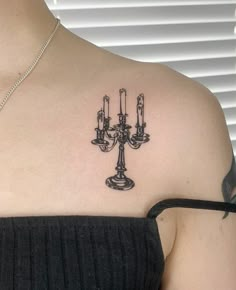 a woman with a tattoo on her shoulder has three candles in the shape of a candelabra