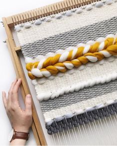 someone is working on an weaving project with yellow and white yarn