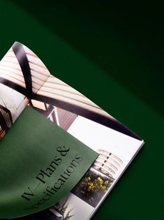 an open brochure with a green cover and black ribbon on the front page