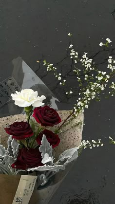 a bouquet of flowers sitting on top of a piece of tin foil next to water