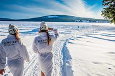 two people in white onesuits walking through the snow