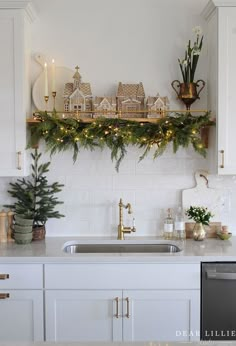 a kitchen decorated for christmas with candles and greenery on the shelf above the sink