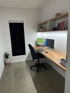 an office with a desk, computer monitor and bookshelf in the corner next to it