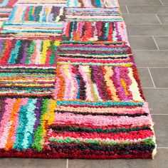 a multicolored area rug on the ground with tile flooring in the background