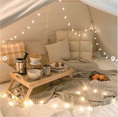 a bed in a room with lights strung from the ceiling and blankets on top of it