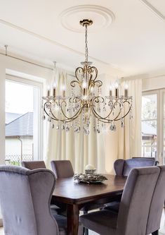 a chandelier hangs from the ceiling above a dining room table with purple chairs