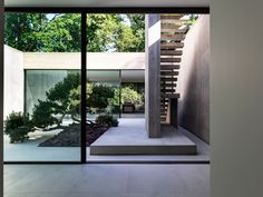 the interior of a modern house with glass walls and doors leading to an outdoor area