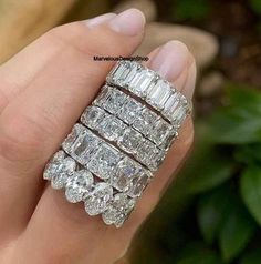 a woman's hand holding a ring with three rows of diamonds on it,