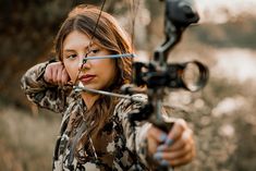 a woman is holding her bow and aiming it at the camera with an arrow in front of her