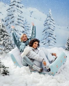 two women are sitting on an inflatable snow sled and posing for the camera