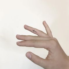 a person's hand with a tiny cross tattoo on it