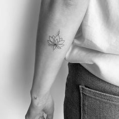 a woman's arm with a small flower tattoo on the left side of her right arm