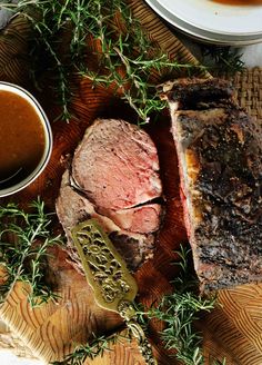 a piece of meat sitting on top of a wooden cutting board next to sauces