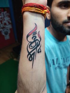 a man with a tattoo on his arm holding up a red and black wristband