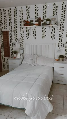 a white bed sitting in a bedroom next to a wall with vines on the walls