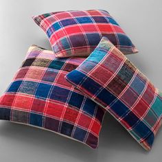 two colorful plaid pillows sitting on top of each other