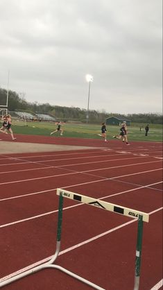 a group of people on a track with a goal in the foreground and another person running behind them