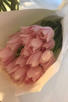 a bouquet of pink tulips is wrapped in white paper and ready to be delivered