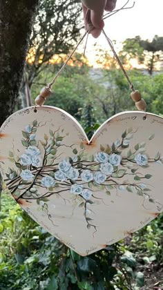 a heart shaped hanging decoration with flowers painted on the outside and in the middle of it