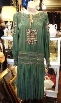 "This is a vintage embroidered and smocked Hungarian peasant dress from the 1920's or early 1930's.  It's green silk, with multi-color embroidery and smocking, all hand done.  It has a scoop neckline, and there are a couple of small spots in front at the hem that I have not tried to remove. (see photos).  The smocked hip band is flexible, so the dress just pops over your head.   A classic boho look from back in the day!  Comes from a smoke free home. Measurements: Bust: up to 46\"   Hip: 38\"   Sleeve Length from Neckline to Sleeve Edge:  28\"   Length:  44.5\" Please ask me any questions you may have before buying as this is a final sale. Please know your measurements and allow for movement.  I ship within 3 business days of cleared payment, usually sooner. If you need something quickly, Bohemian Dresses With Smocked Cuffs, Green Embroidered Vintage Dress, Vintage Green Embroidered Dress, Vintage Embroidered Green Dress, Vintage Embroidered Fall Dresses, Bohemian Daywear Dress With Smocked Cuffs, Fitted Smock Peasant Dress, High Waist Dress Pattern, Heavy Winter Coat