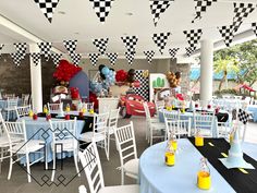 a room filled with lots of tables covered in blue and white tablecloths next to cars