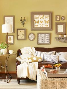 a living room with yellow walls and pictures on the wall above the brown leather couch