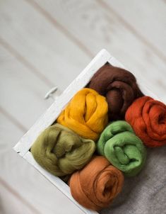 several different colored wools in a white box