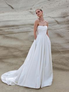 a woman standing in the sand wearing a white dress