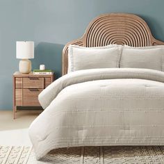 a bedroom with blue walls and white linens on the bed, along with a wicker headboard