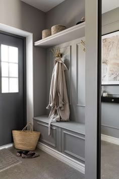 an image of a room with gray walls and coat racks on the wall, and a basket in front of it