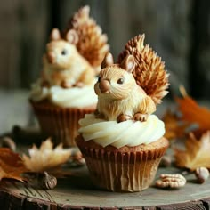 two cupcakes with white frosting and small figurines of squirrels on top