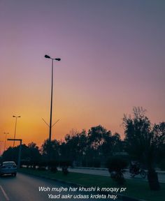 the sun is setting over an empty street with cars driving down it and trees in the background