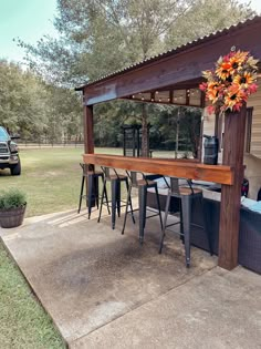 a table and chairs under a wooden structure with flowers on the top, in front of a truck