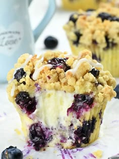 blueberry crumb muffins with white frosting and fresh blueberries on top