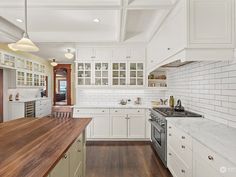 a large kitchen with white cabinets and wood counter tops, along with an island in the middle