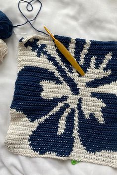 a crocheted square with yarn and scissors on it next to a ball of thread