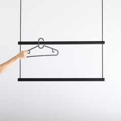 a hand is holding a hanger with clothes on it and another hanging from the ceiling