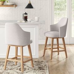 two gray chairs sitting on top of a rug in front of a kitchen countertop