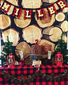 a table topped with lots of logs covered in red and black plaid cloth next to christmas decorations