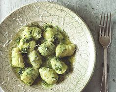 a white plate topped with ravioli covered in pesto