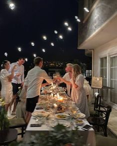 a group of people standing around a table with food and drinks on top of it